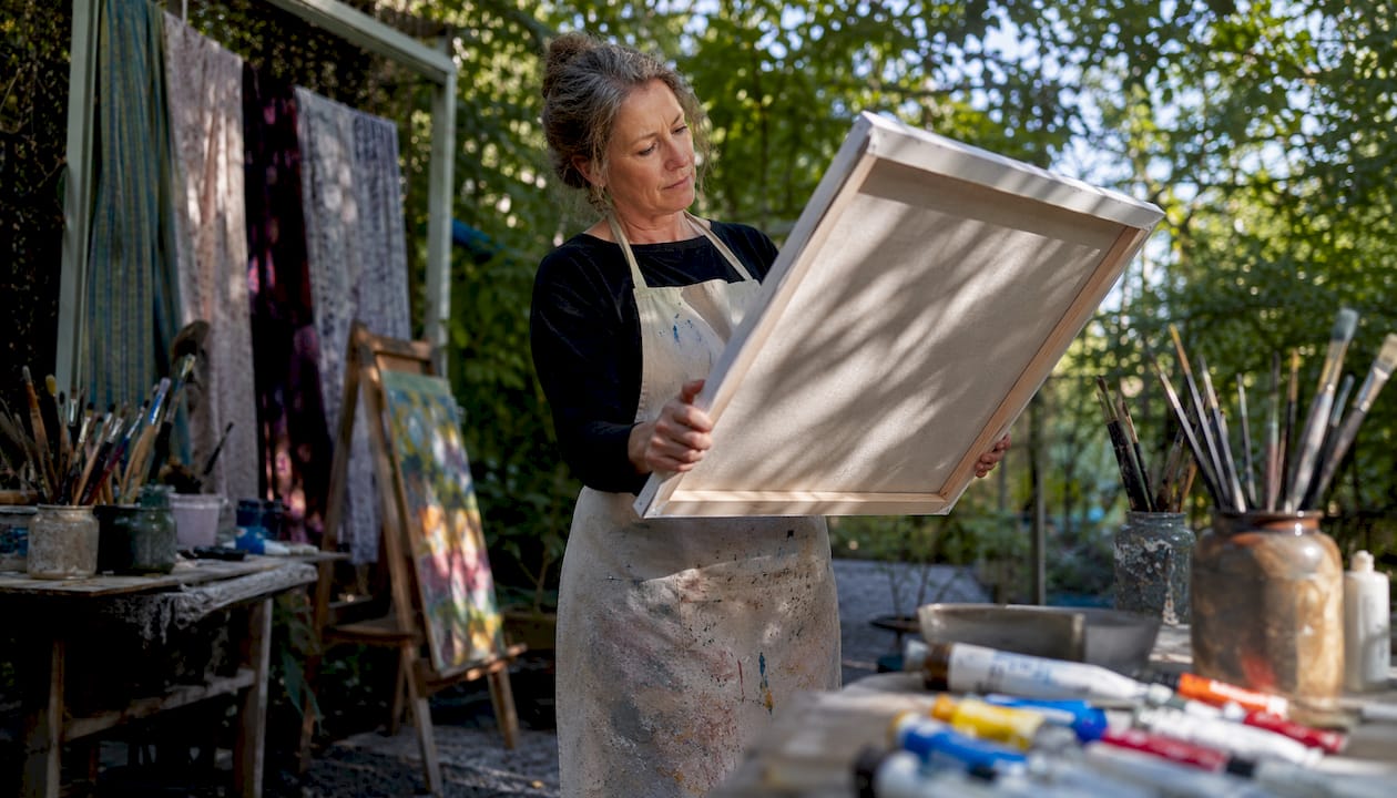 Artist inspecting stretched canvas in studio